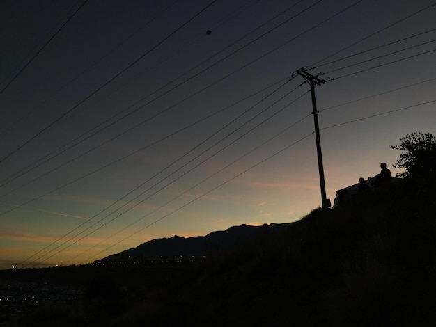 Foto lage hoek van de elektriciteitspylon tegen de hemel tijdens de zonsondergang