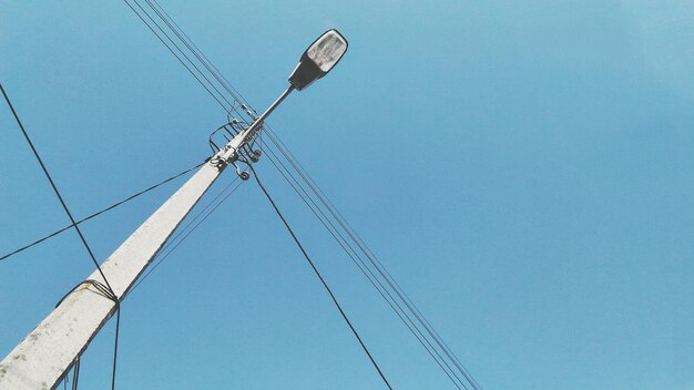 Foto lage hoek van de elektriciteitspylon tegen een heldere blauwe hemel