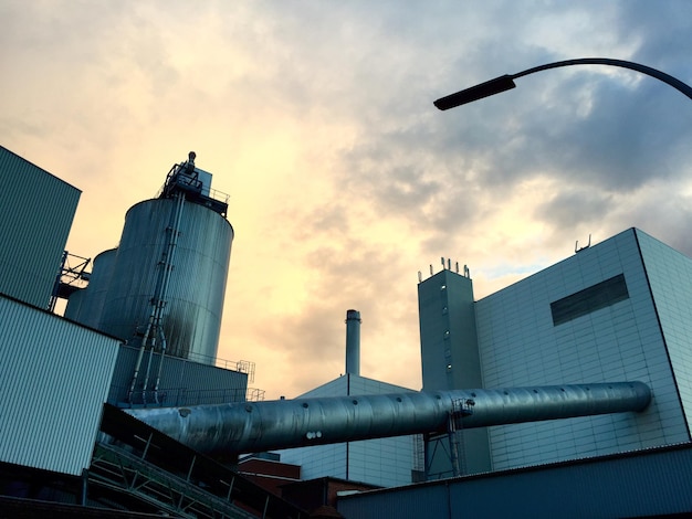 Foto lage hoek van de fabriek en het gebouw tegen bewolkte lucht bij zonsondergang