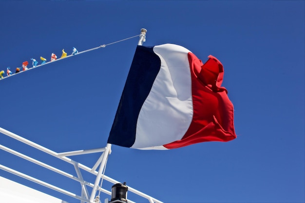 Foto lage hoek van de franse vlag op de reling tegen een heldere blauwe lucht