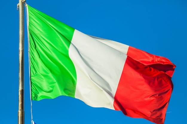 Foto lage hoek van de italiaanse vlag tegen een heldere blauwe hemel