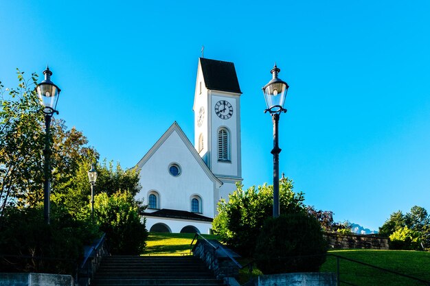 Foto lage hoek van de kerk en de lantaarnpalen tegen een heldere blauwe hemel