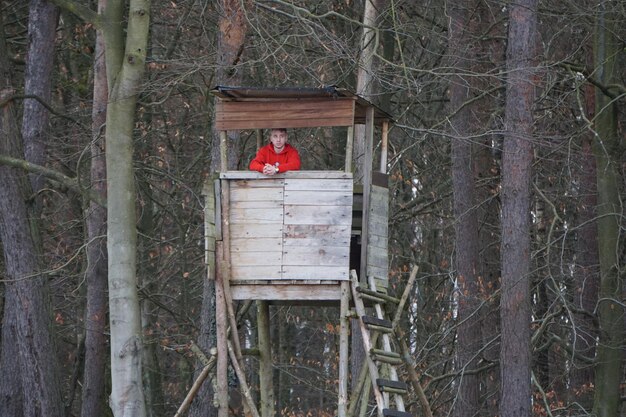 Foto lage hoek van de man in een klein houten huis in het bos