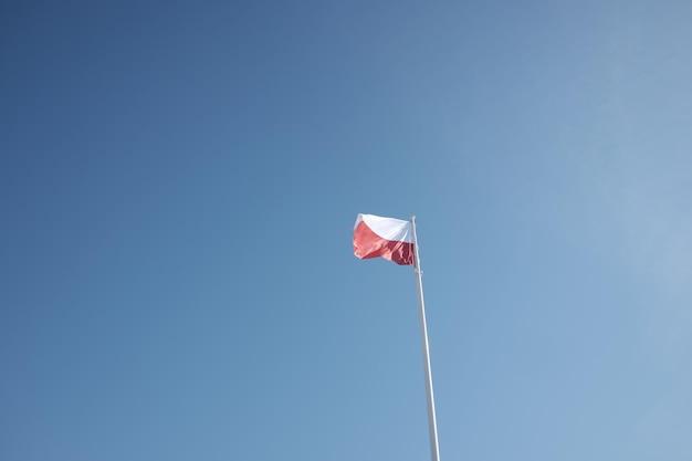 Lage hoek van de Poolse vlag die zwaait tegen een heldere blauwe hemel