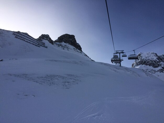 Foto lage hoek van de skilift over een met sneeuw bedekte berg tegen de lucht