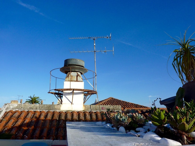 Lage hoek van de televisie-antenne op het dak tegen de blauwe hemel