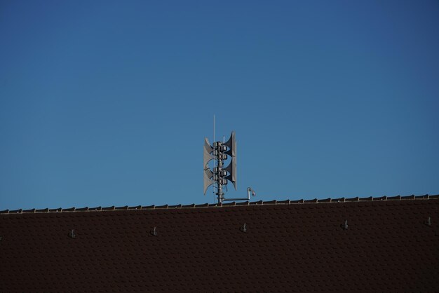 Lage hoek van de windmolen op het dak van het gebouw tegen een heldere blauwe lucht