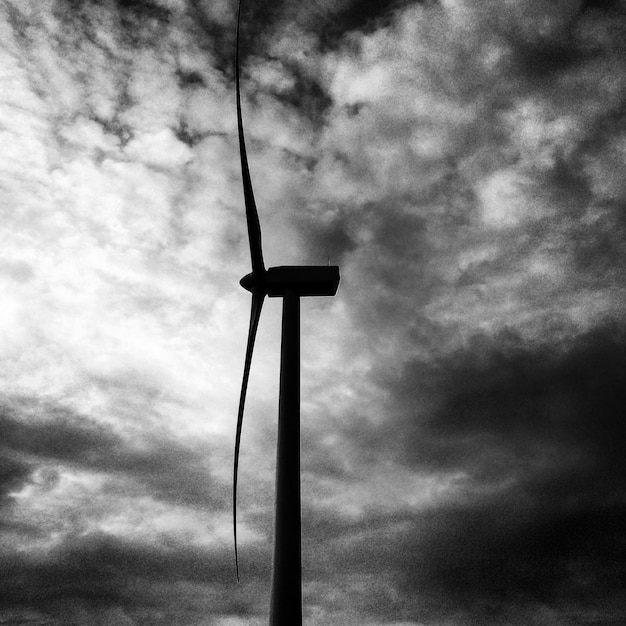 Foto lage hoek van de windmolen tegen bewolkte lucht