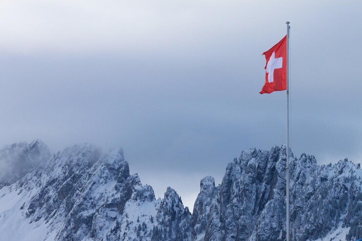 Foto lage hoek van de zwitserse vlag tegen een besneeuwde berg