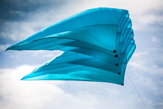 Foto lage hoek van een blauwe vlieger die tegen een bewolkte lucht vliegt