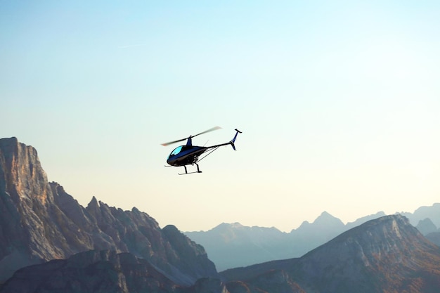 Lage hoek van een helikopter die over bergen vliegt tegen een heldere lucht