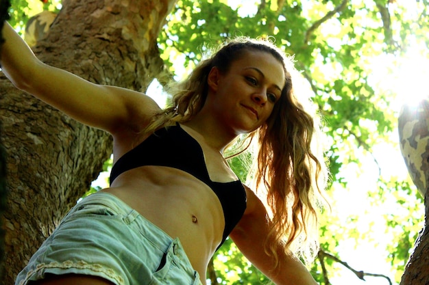 Foto lage hoek van een jonge vrouw tegen een boom