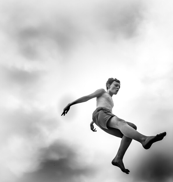 Foto lage hoek van een jongen die tegen de lucht springt