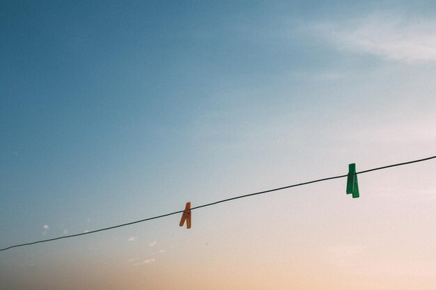 Foto lage hoek van een kledingspeld die tijdens de zonsondergang aan een touw hangt tegen de hemel