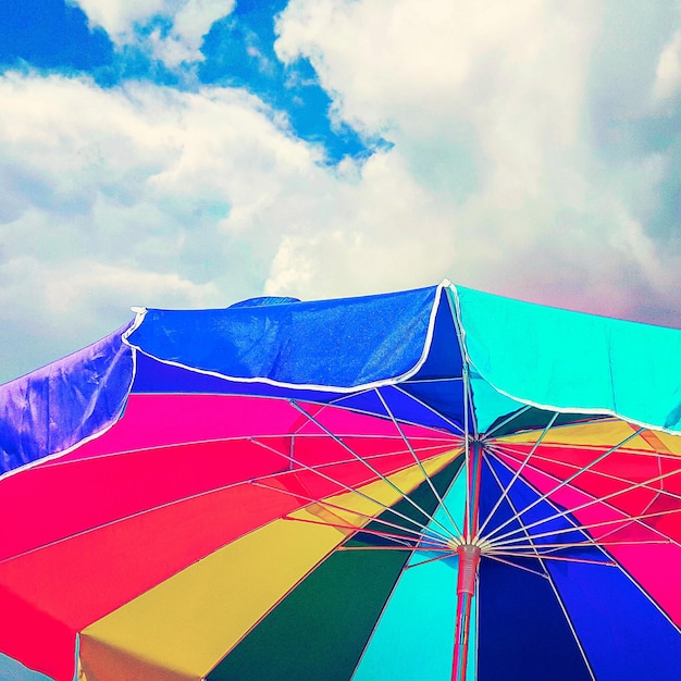 Foto lage hoek van een kleurrijke strandparaplu tegen een bewolkte lucht
