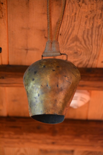 Foto lage hoek van een koeienklok die aan het houten plafond hangt