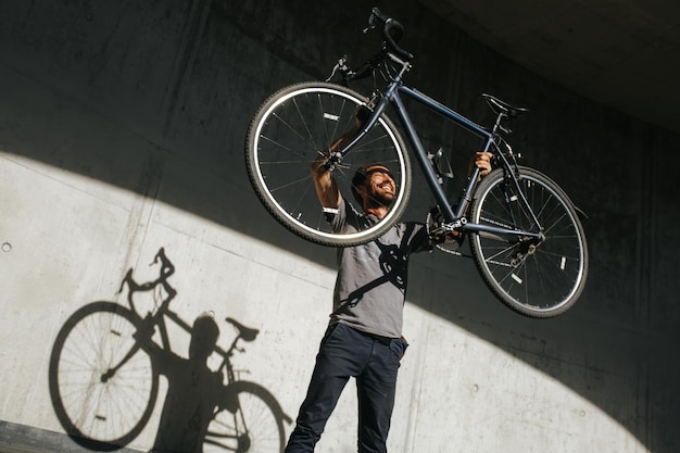 Lage hoek van een man die een fiets tegen de muur pakt