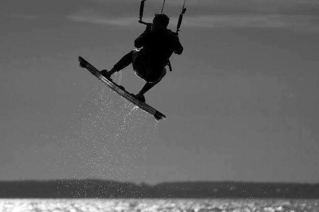 Lage hoek van een man die kitesurft in de zee tegen de lucht