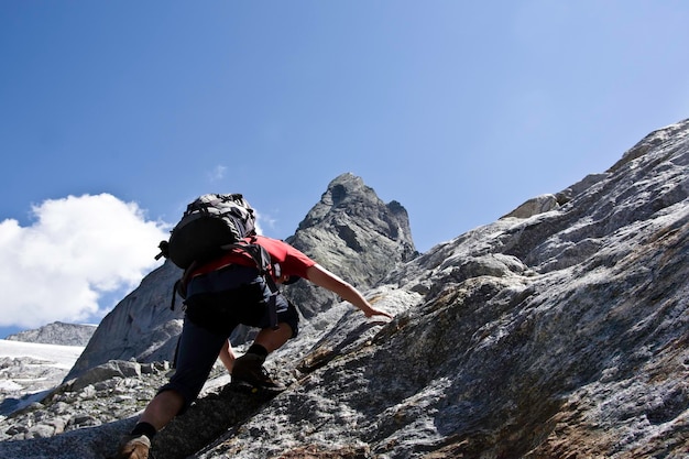 Lage hoek van een man die op een zonnige dag een berg beklimt tegen de lucht
