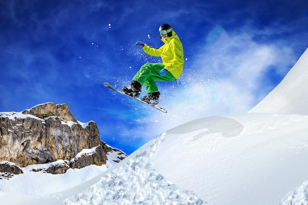 Lage hoek van een man die snowboardt in de lucht boven een met sneeuw bedekte berg