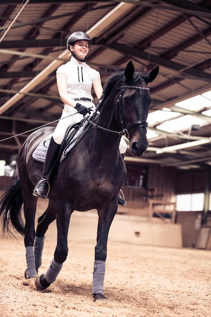 Lage hoek van een meisje dat paard rijdt in de stal