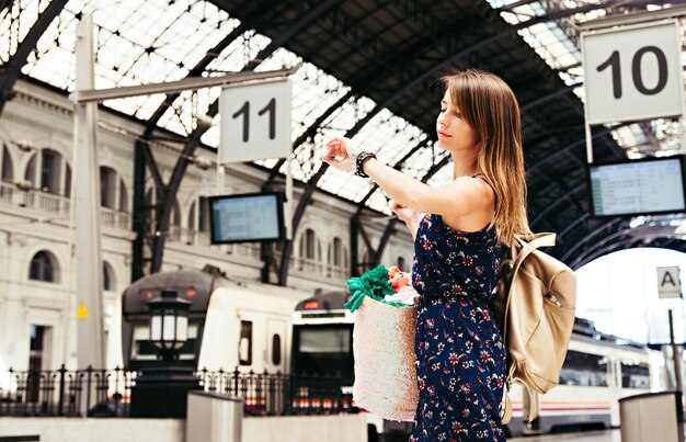 Foto lage hoek van een mooie vrouw die de tijd controleert op het treinstation