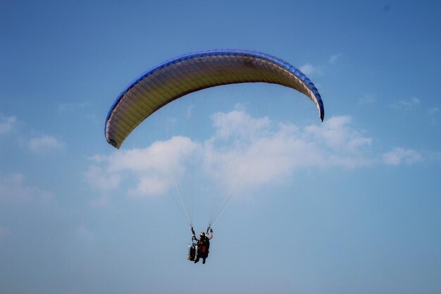 Foto lage hoek van een persoon die met een paraglider tegen de lucht vliegt