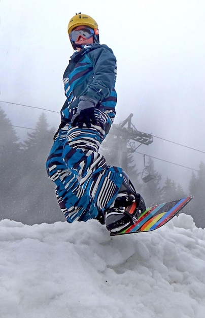 Foto lage hoek van een persoon die snowboardt tijdens mistig weer