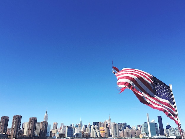 Lage hoek van een verscheurde Amerikaanse vlag die waait tegen de heldere lucht in de stad