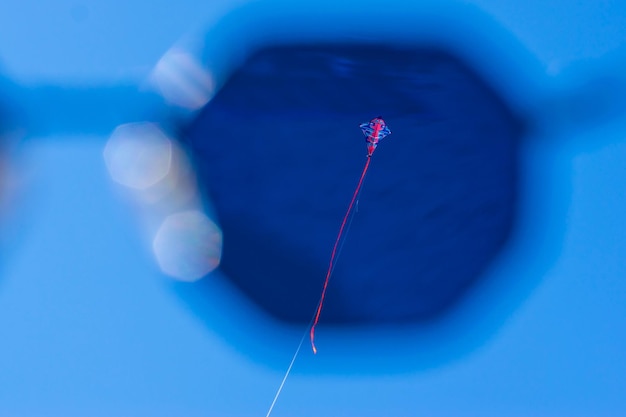 Foto lage hoek van een vlieger die in de blauwe lucht vliegt
