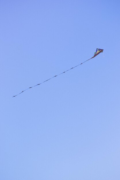 Foto lage hoek van een vlieger die in een heldere blauwe hemel vliegt