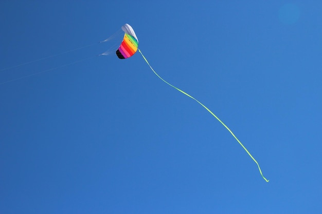 Foto lage hoek van een vlieger die tegen een heldere blauwe lucht vliegt