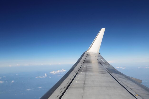 Foto lage hoek van een vliegtuig dat tegen de blauwe hemel vliegt