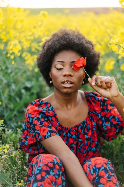 Lage hoek van een vrouw die op roze bloeiende planten zit