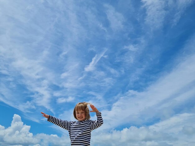 Lage hoek van een vrouw die tegen een bewolkte lucht staat