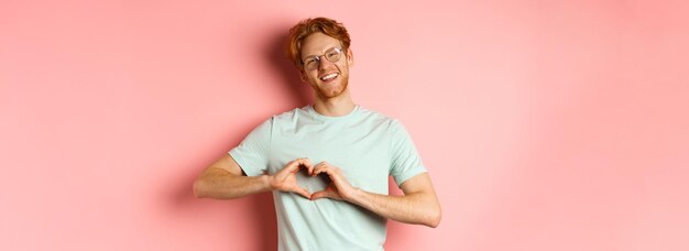 Foto lage hoek van een vrouw die tegen een roze achtergrond staat