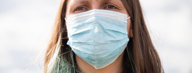 Foto lage hoek van een vrouw met een masker die tegen een hek staat