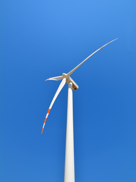 Lage hoek van een windturbine tegen een heldere blauwe lucht