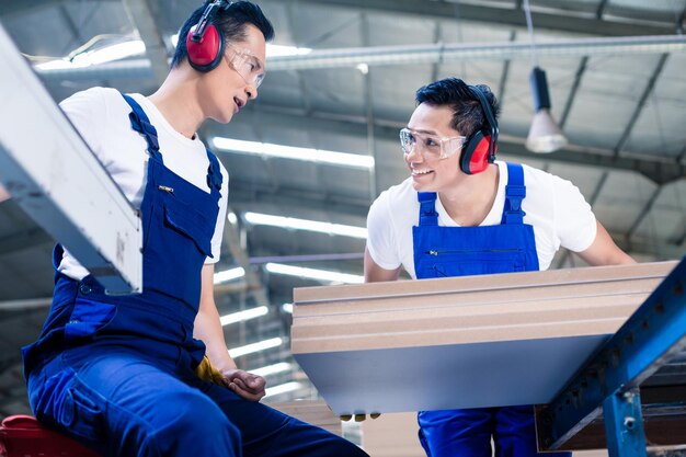 Lage hoek van glimlachende mannen die in een fabriek werken
