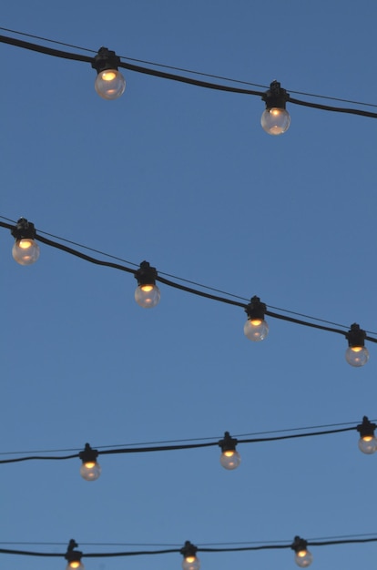 Foto lage hoek van gloeilampen die tegen de lucht hangen