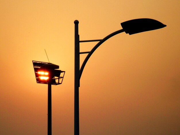 Foto lage hoek van het silhouetstraatlicht tegen de oranje hemel