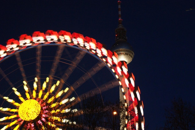 Foto lage hoek van het verlichte reuzenwiel tegen de fernsehturm's nachts