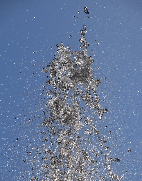 Foto lage hoek van het water spuiten tegen een heldere blauwe hemel