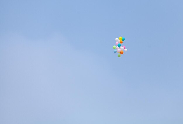 Foto lage hoek van kleurrijke ballonnen die tegen de blauwe hemel vliegen