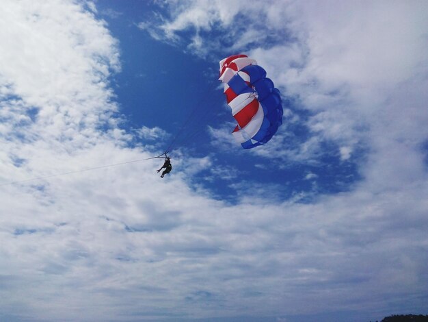 Foto lage hoek van mensen die paragliden tegen bewolkte lucht