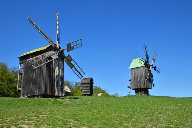 Foto lage hoek van ouderwetse windturbines op een grasrijke heuvel