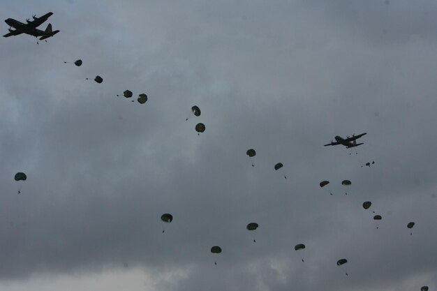 Foto lage hoek van parachutisten die uit vliegtuigen vallen tegen een bewolkte lucht