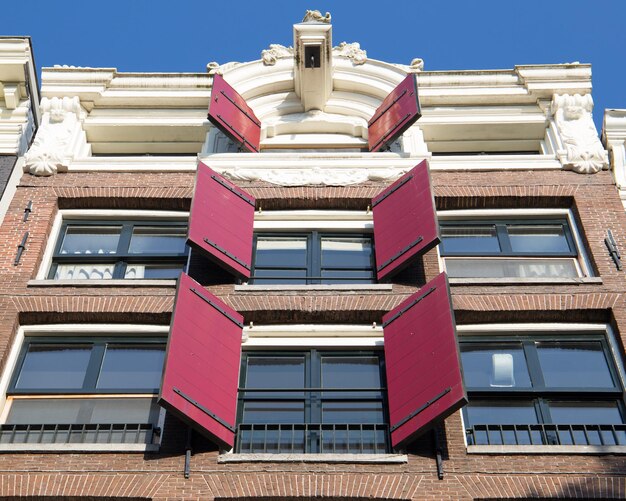 Foto lage hoek van rode luiken op een kanaalhuis in amsterdam tegen een blauwe hemel