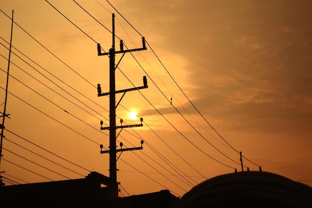 Foto lage hoek van silhouet elektriciteitsleidingen tegen de hemel tijdens zonsondergang