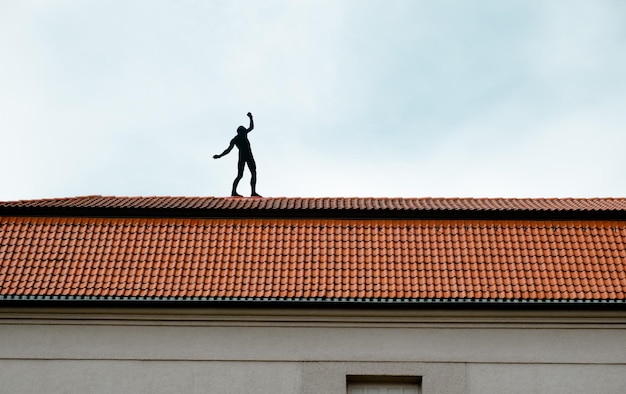 Lage hoek van silhouet man op het dak van het huis tegen de lucht